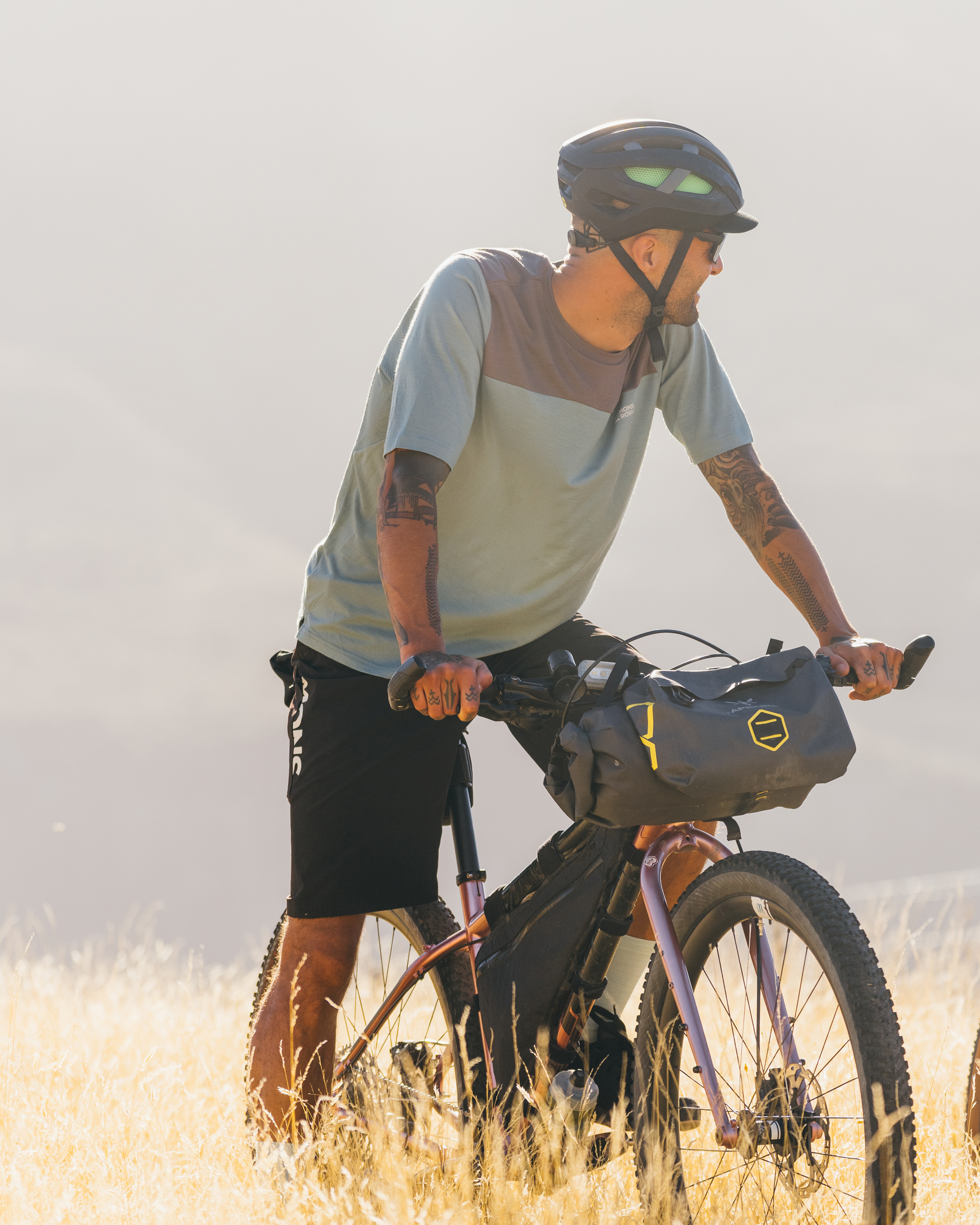 A man on a bike pauses in a field of grass.