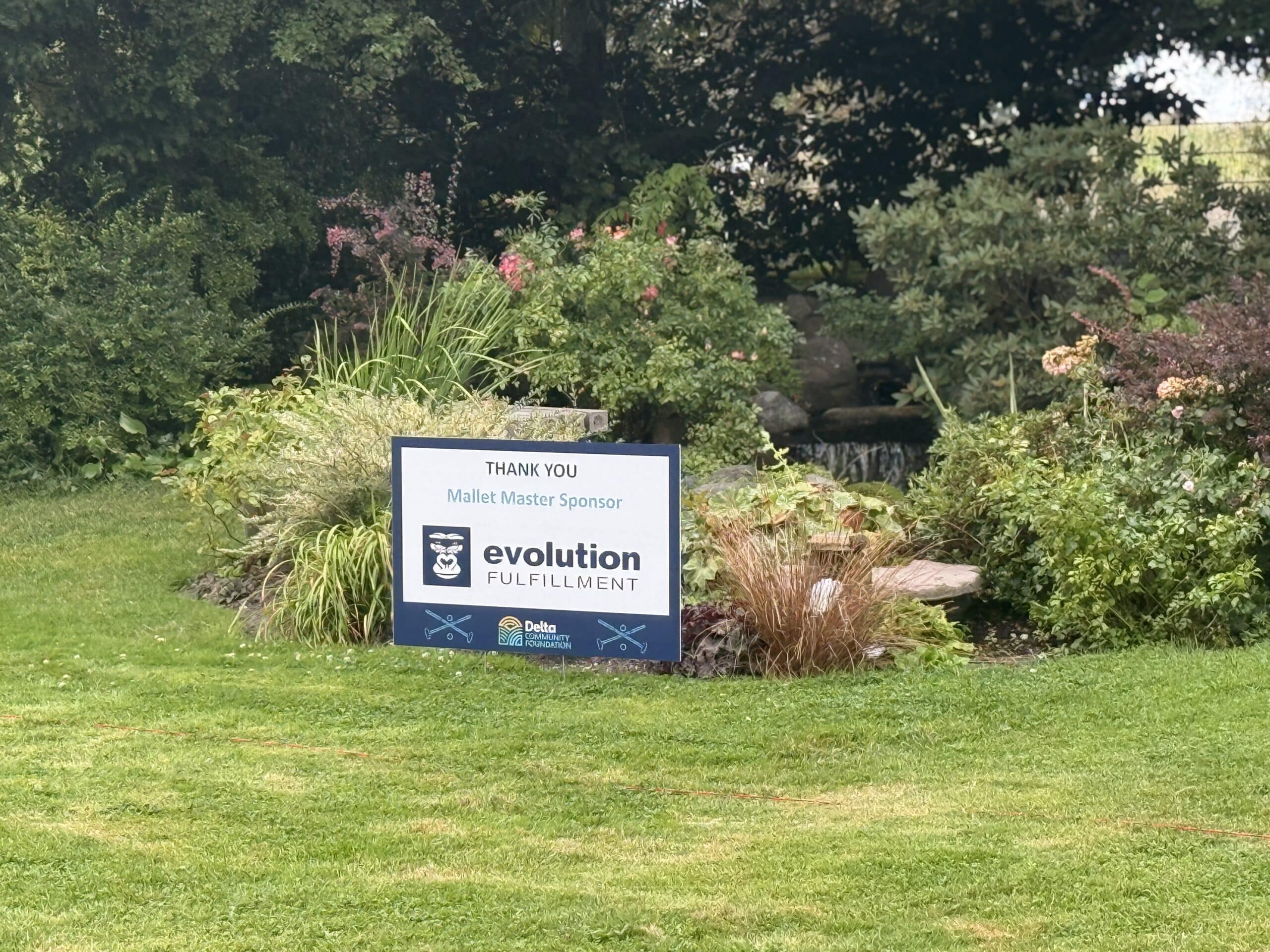 A sponsorship sign featuring the Evolution Fulfillment logo is situated on a grass lawn.