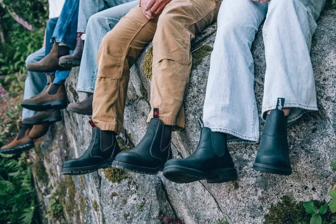 Several people sit on a large rock. Only their legs are visible dangling over the edge, and they are wearing Redback boots.