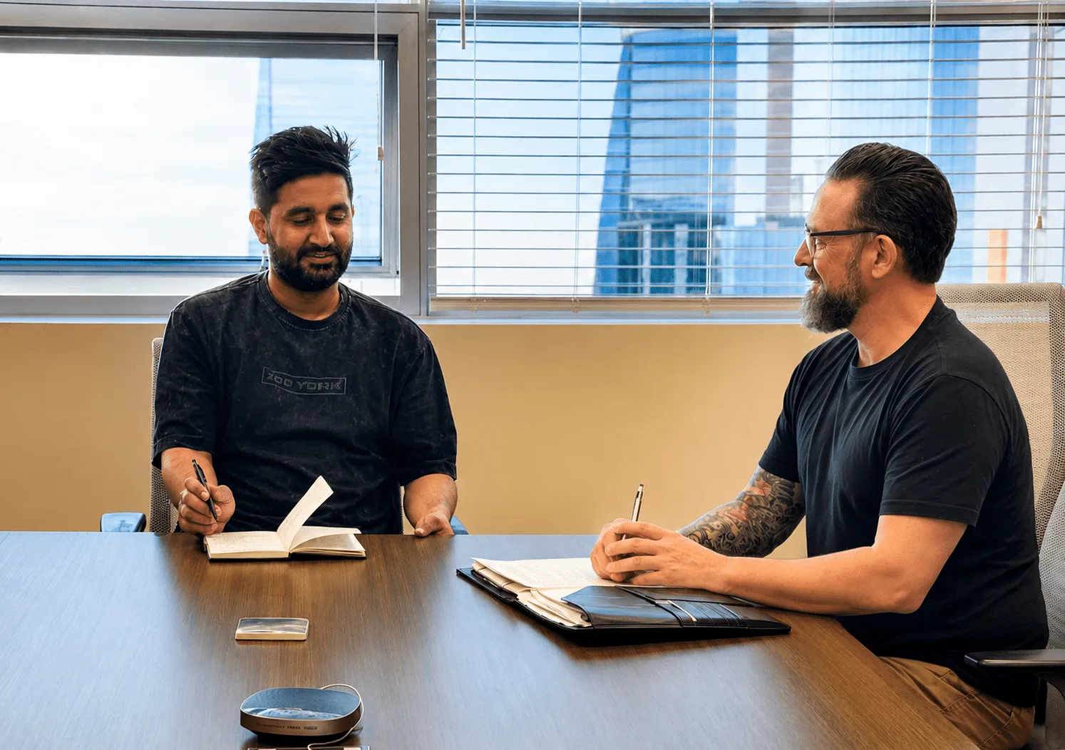 Two men sit at a table in an office building.