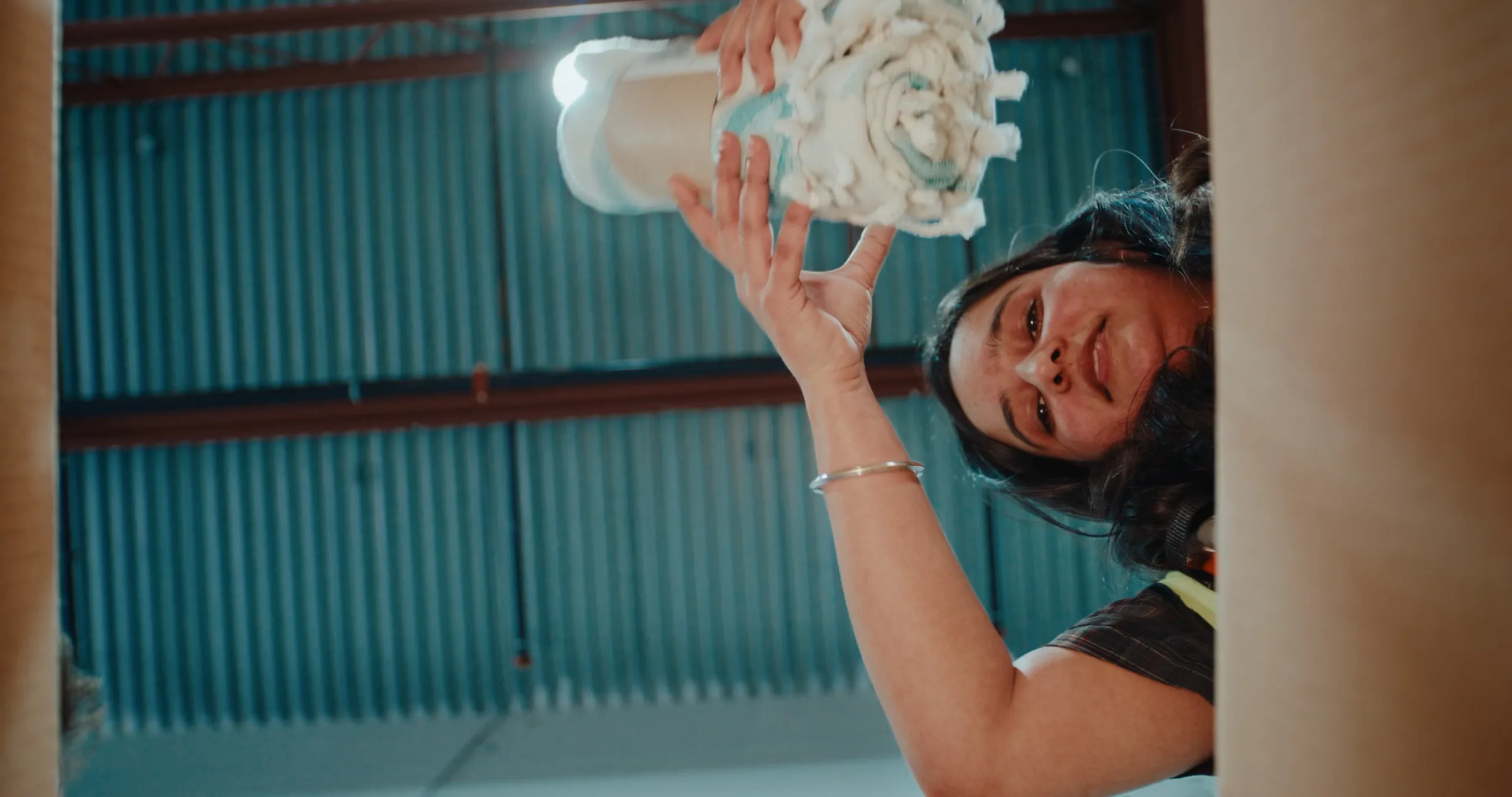 A woman working in a warehouse places products into an open box. The photo is shot as if inside the box.